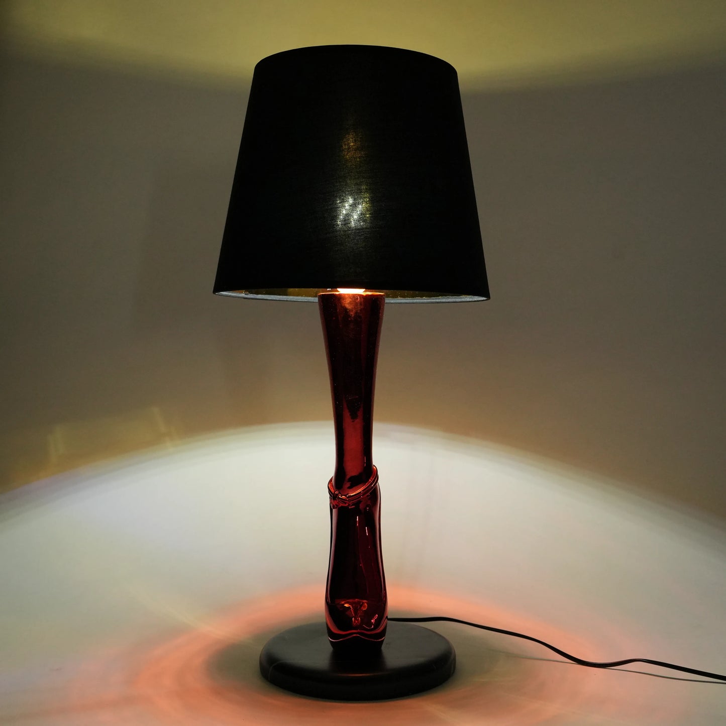 Black lamp with a red base on a white surface