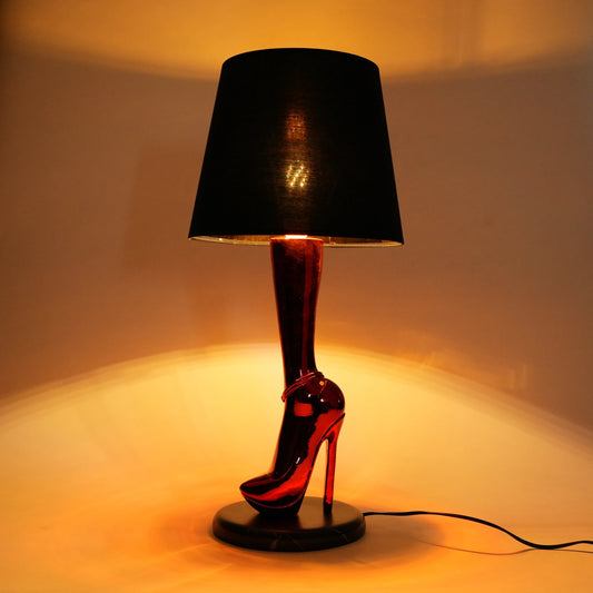red heel shaped table lamp with black shade and warm ambient lighting