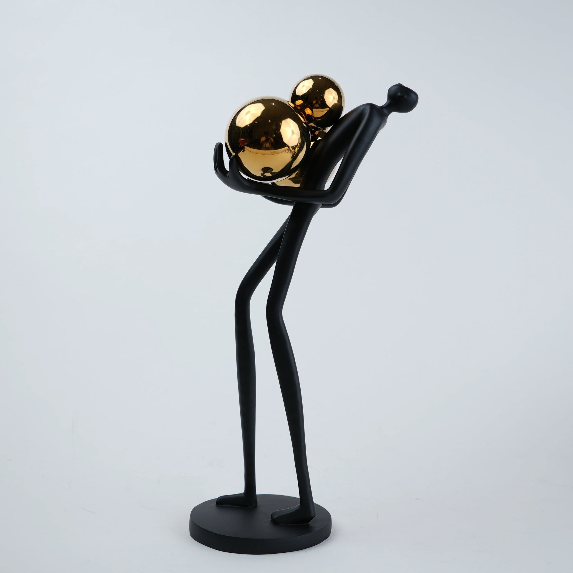 matte black figurine holding gold spheres modern decor