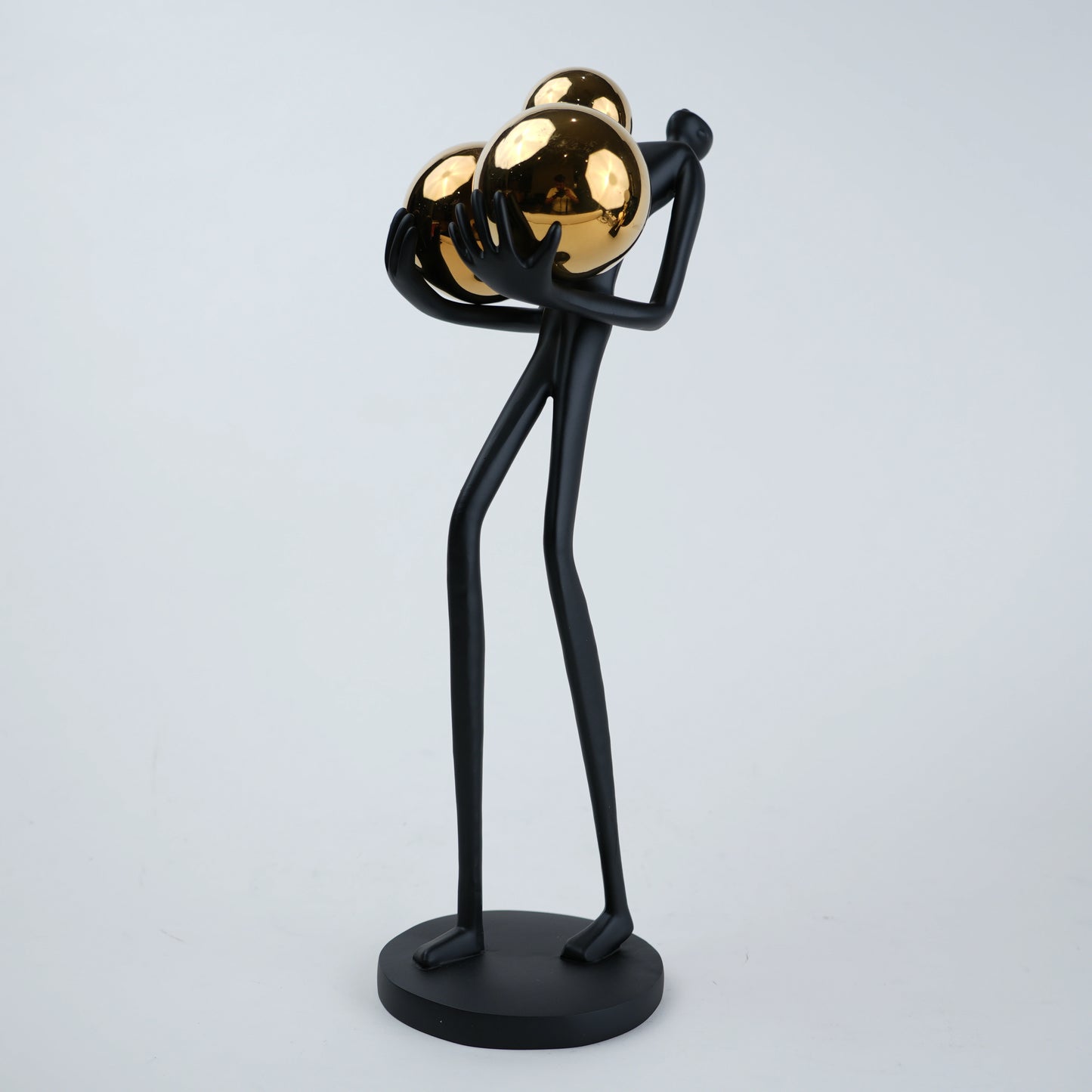 matte black figurine holding gold spheres modern decor