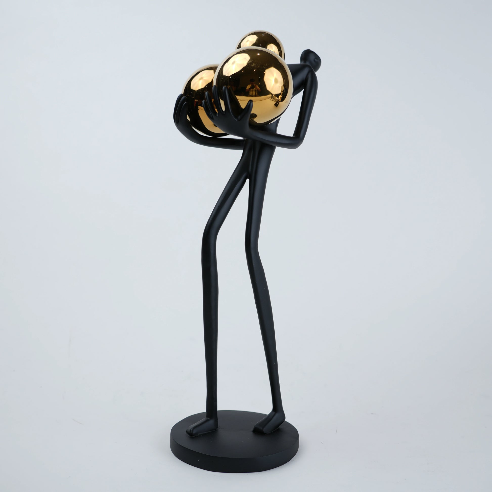 matte black figurine holding gold spheres modern decor