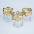 Three clear glass tumblers with gold Greek key pattern bands