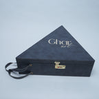 A dark navy blue triangular presentation box with a textured finish, featuring the brand name 'Ghar art' in white script on the top surface. The box has a small gold-toned combination lock on the front and a matching dark handle
