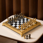 An ornate chess set with a gold-plated frame and metallic gold and bronze figurines, arranged on a black and white checkered board over a white marble surface.