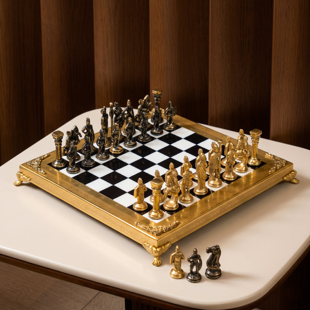 An ornate chess set with a gold-plated frame and metallic gold and bronze figurines, arranged on a black and white checkered board over a white marble surface.
