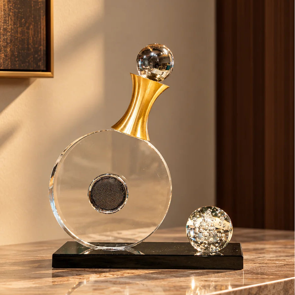 Modern tabletop décor featuring a clear circular design, gold accent and black base.