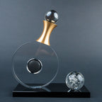 Modern tabletop décor featuring a clear circular design, gold accent and black base.