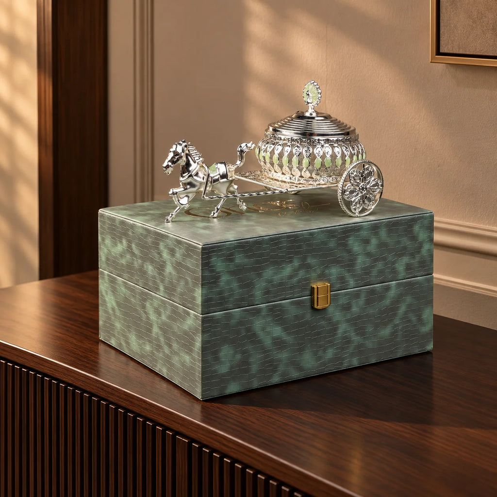 Luxury silver horse-drawn carriage showpiece featuring an intricately crafted ornamental carriage with an elegant domed lidded design, detailed filigree patterns, decorative crystal-like embellishments, finely sculpted horse figurine and beautifully designed spoked wheels. The polished silver finish and elaborate craftsmanship make it an elegant statement piece for luxury home décor, display cabinets and sophisticated interiors.