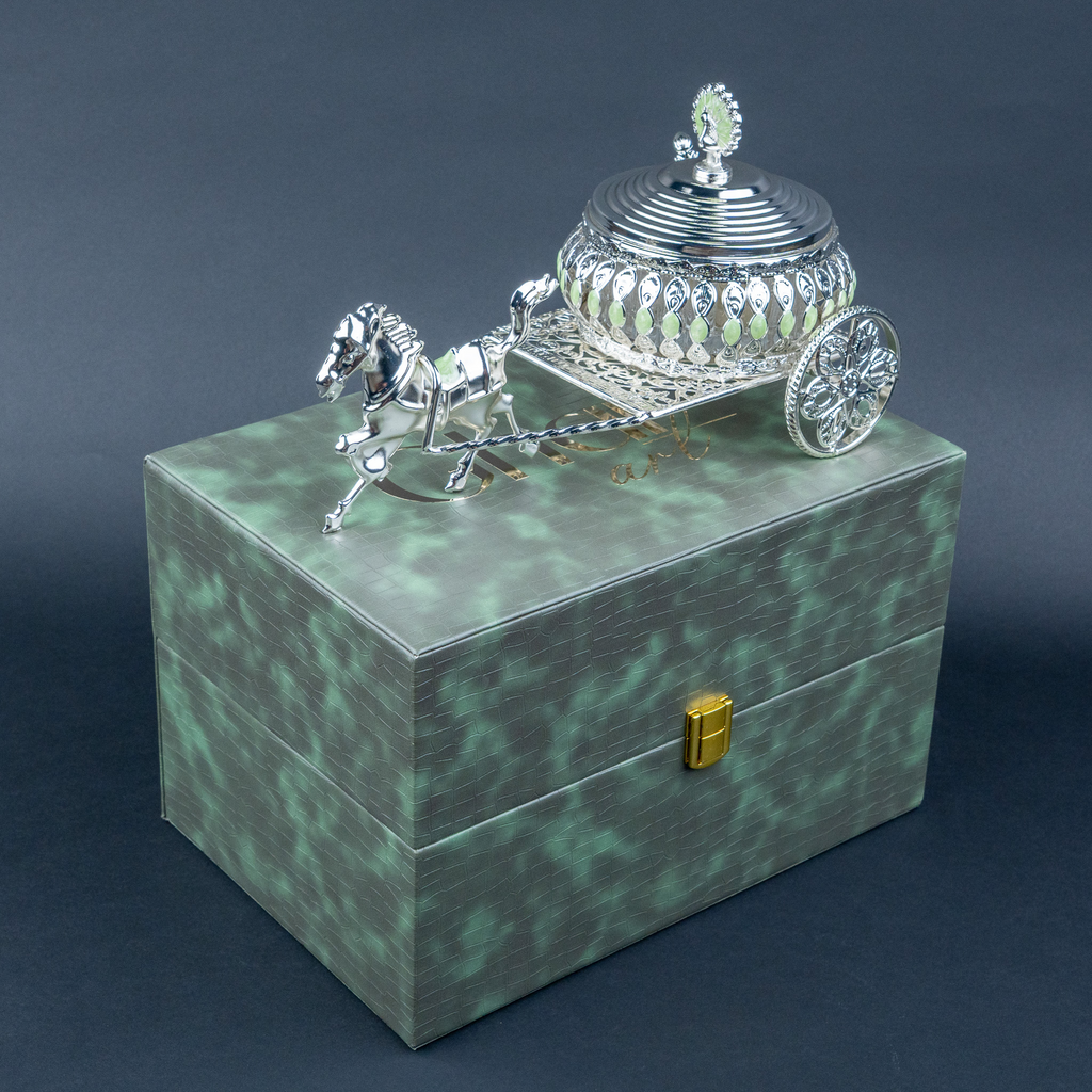 Luxury silver horse-drawn carriage showpiece featuring an intricately crafted ornamental carriage with an elegant domed lidded design, detailed filigree patterns, decorative crystal-like embellishments, finely sculpted horse figurine and beautifully designed spoked wheels. The polished silver finish and elaborate craftsmanship make it an elegant statement piece for luxury home décor, display cabinets and sophisticated interiors.