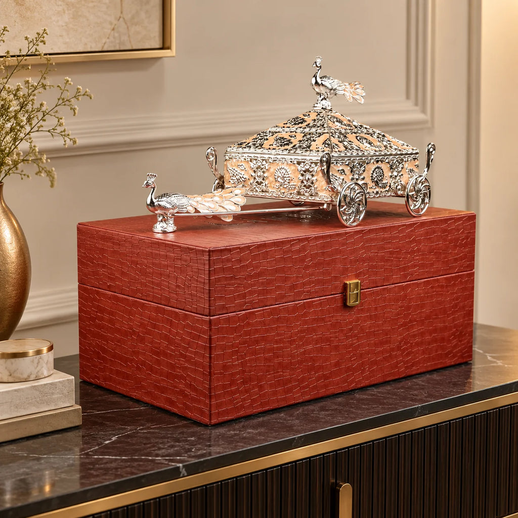 Intricately crafted silver decorative horse-drawn chariot showpiece featuring an ornate miniature carriage with an elegant pyramid-shaped roof, detailed floral and filigree engravings, decorative silver horse figurines, and beautifully sculpted ornamental wheels. Its polished metallic finish and intricate craftsmanship make it a luxurious statement piece for living room décor, display cabinets and premium interiors.