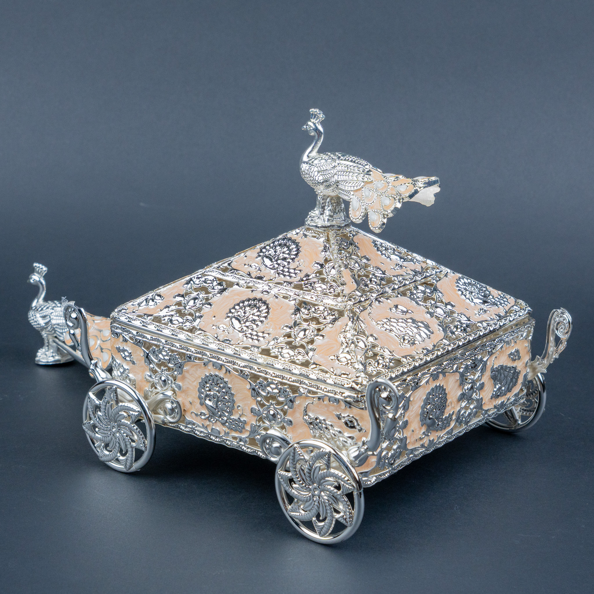 Intricately crafted silver decorative horse-drawn chariot showpiece featuring an ornate miniature carriage with an elegant pyramid-shaped roof, detailed floral and filigree engravings, decorative silver horse figurines, and beautifully sculpted ornamental wheels. Its polished metallic finish and intricate craftsmanship make it a luxurious statement piece for living room décor, display cabinets and premium interiors.