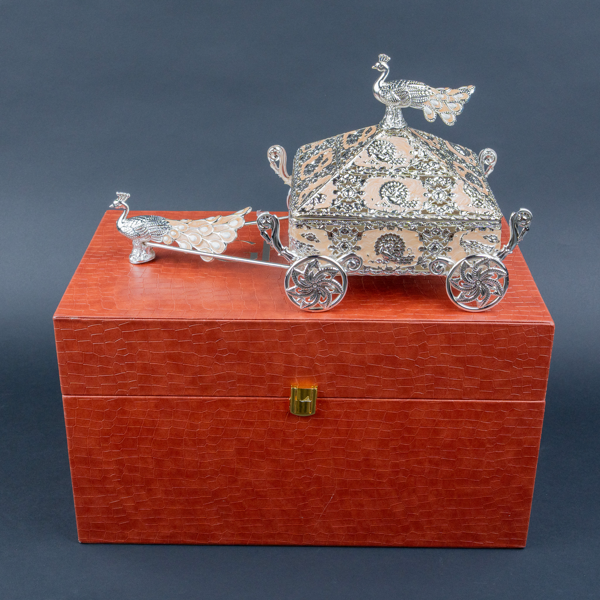 Intricately crafted silver decorative horse-drawn chariot showpiece featuring an ornate miniature carriage with an elegant pyramid-shaped roof, detailed floral and filigree engravings, decorative silver horse figurines, and beautifully sculpted ornamental wheels. Its polished metallic finish and intricate craftsmanship make it a luxurious statement piece for living room décor, display cabinets and premium interiors.