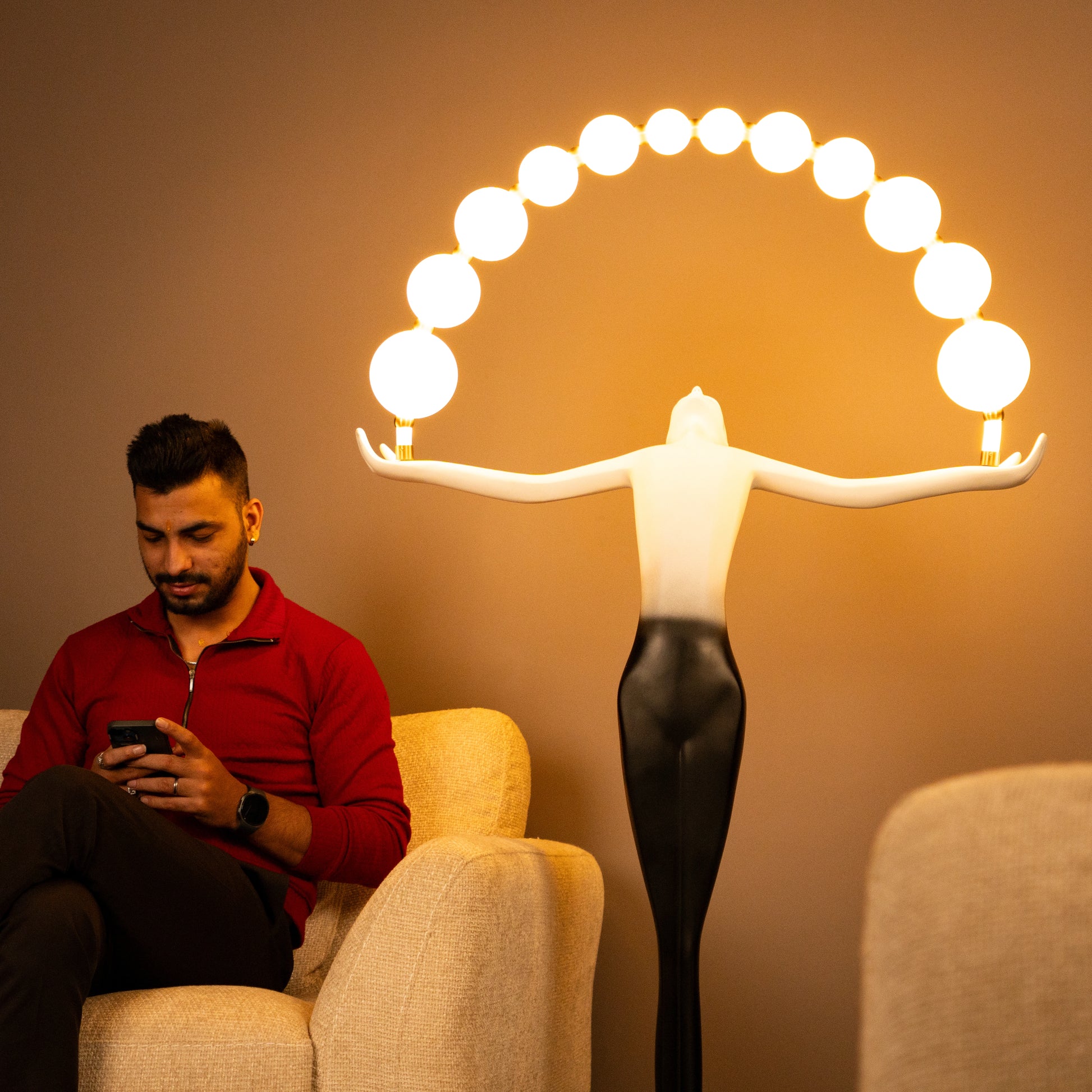 Black and white resin human figure lamp featuring multiple glowing bulbs in an arc — statement floor light sculpture by Ghar Art.
