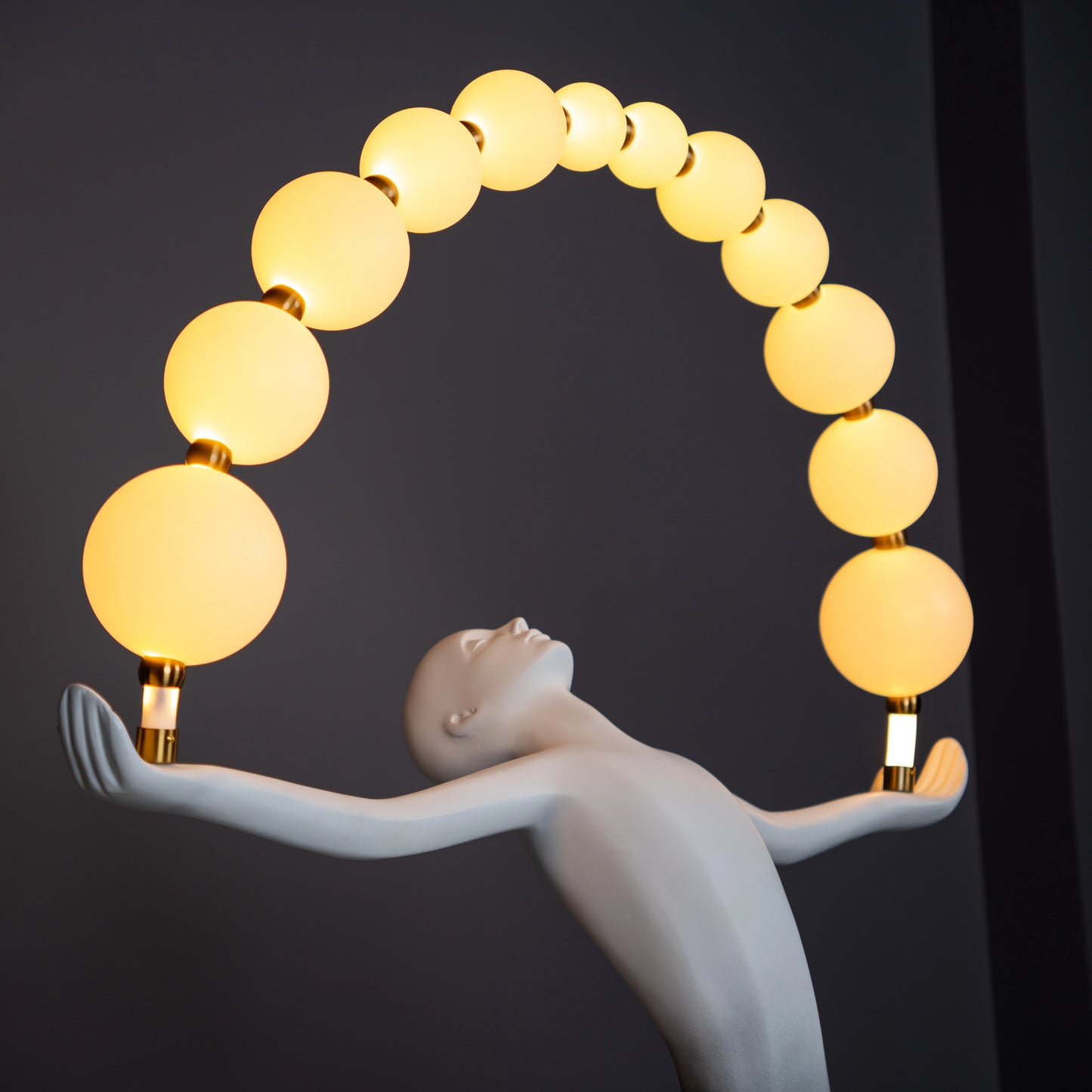 Black and white resin human figure lamp featuring multiple glowing bulbs in an arc — statement floor light sculpture by Ghar Art.