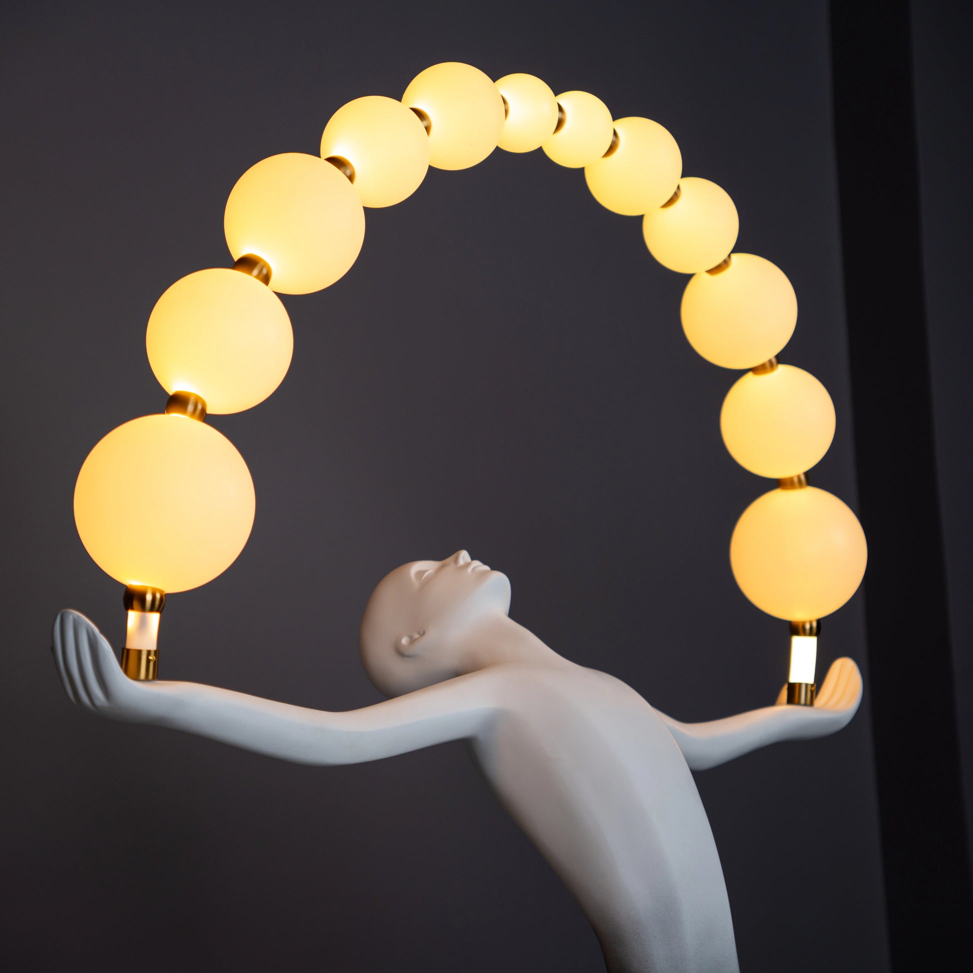Black and white resin human figure lamp featuring multiple glowing bulbs in an arc — statement floor light sculpture by Ghar Art.