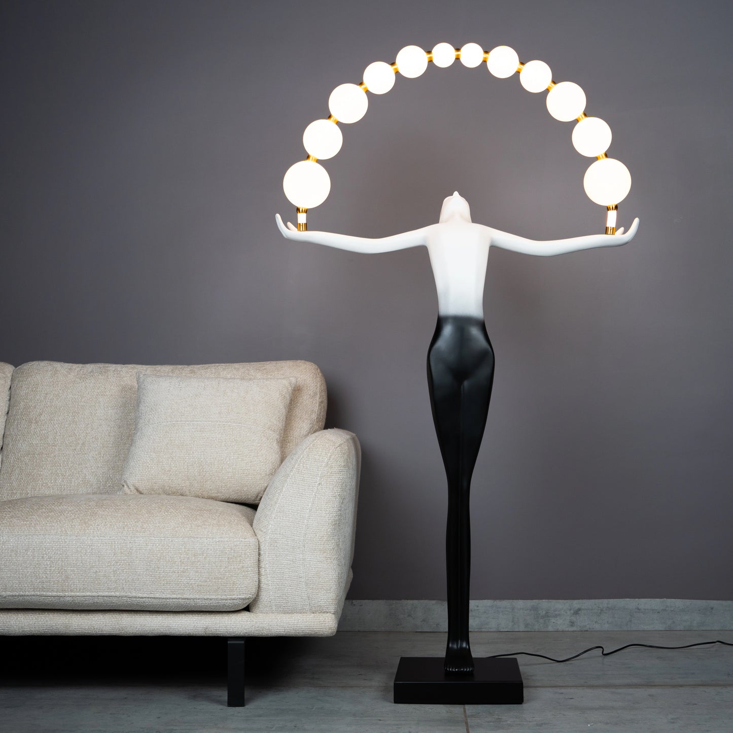 Black and white resin human figure lamp featuring multiple glowing bulbs in an arc — statement floor light sculpture by Ghar Art.