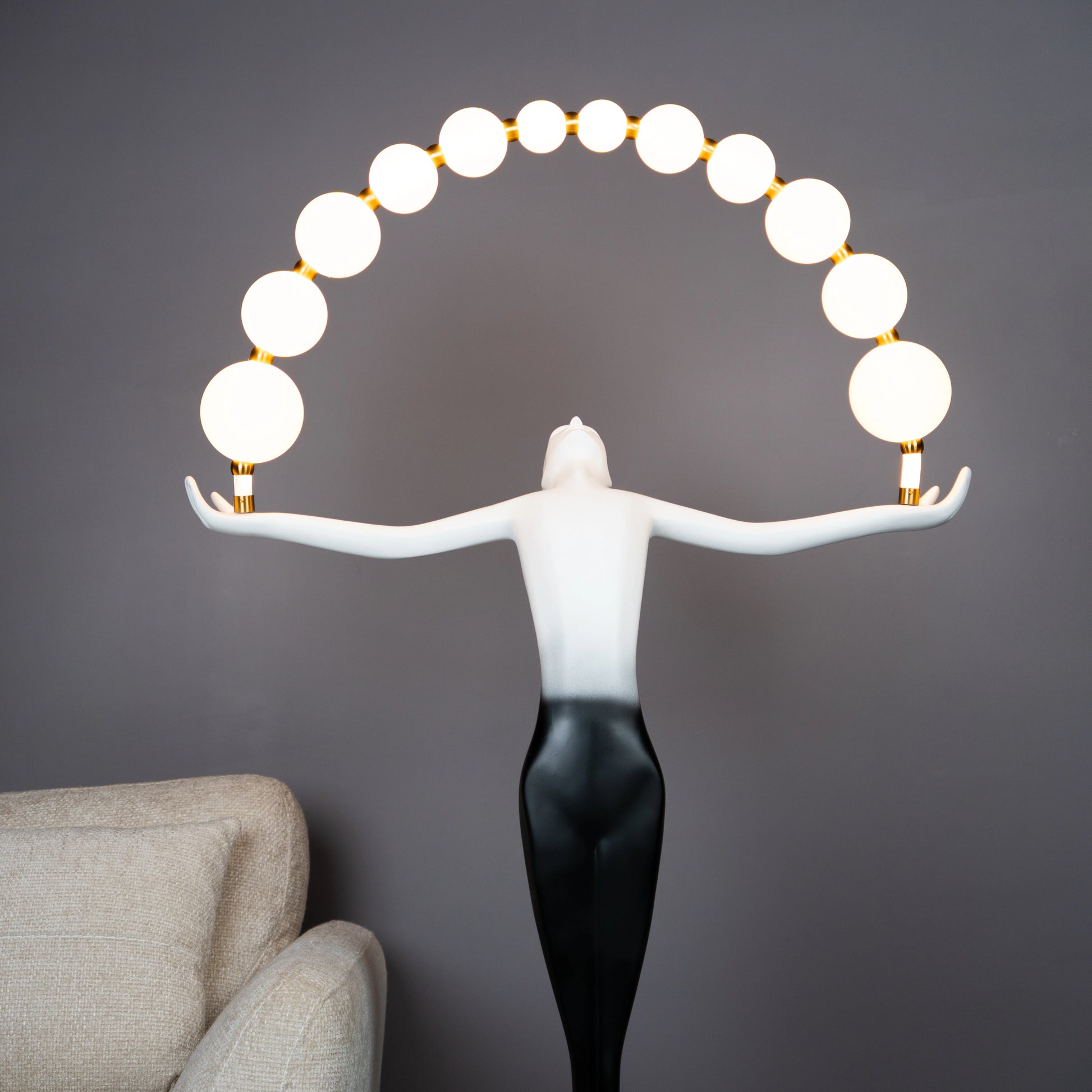 Black and white resin human figure lamp featuring multiple glowing bulbs in an arc — statement floor light sculpture by Ghar Art.
