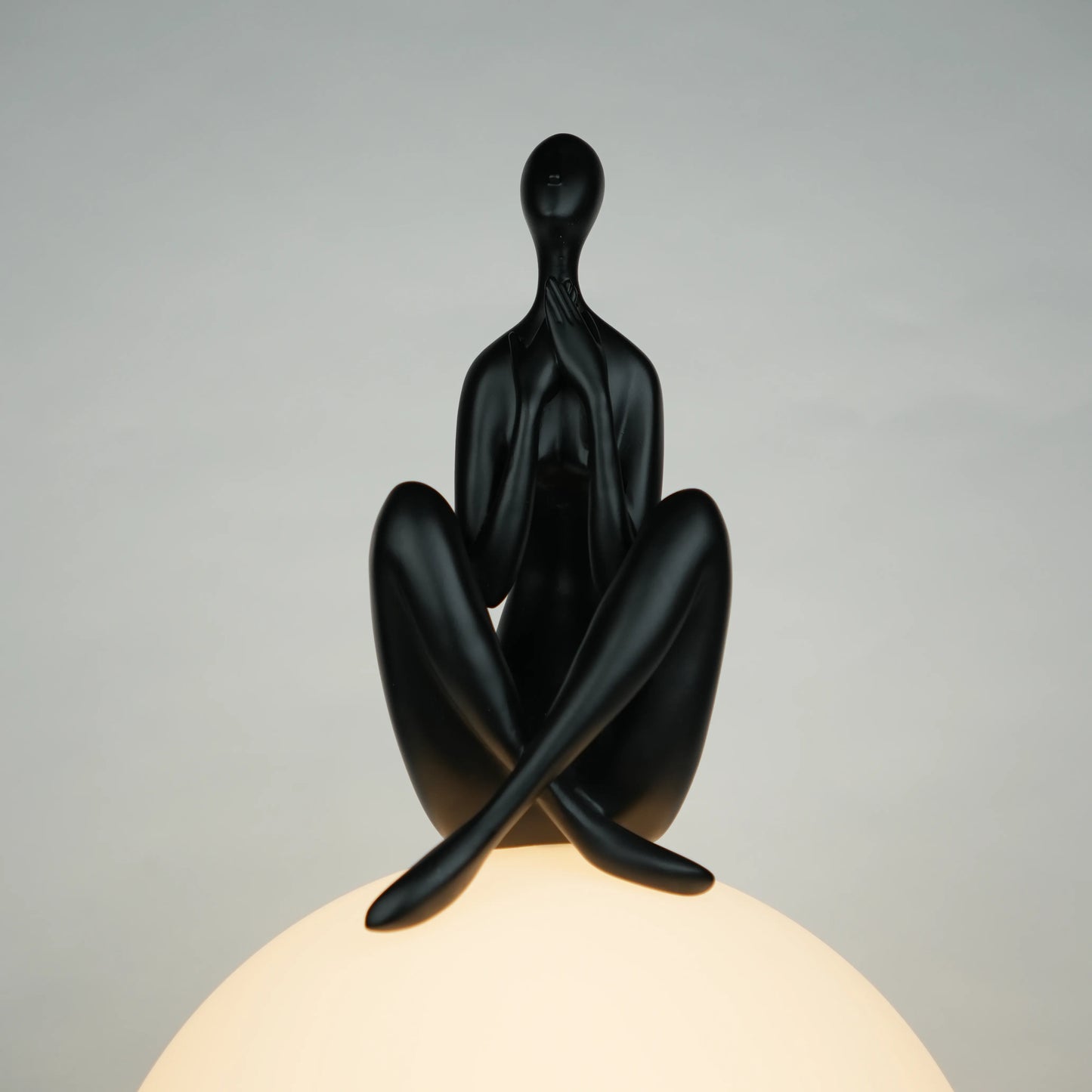 Black human sculpture seated on glowing sphere – Glow Contemplation Lamp