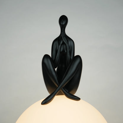 Black human sculpture seated on glowing sphere – Glow Contemplation Lamp