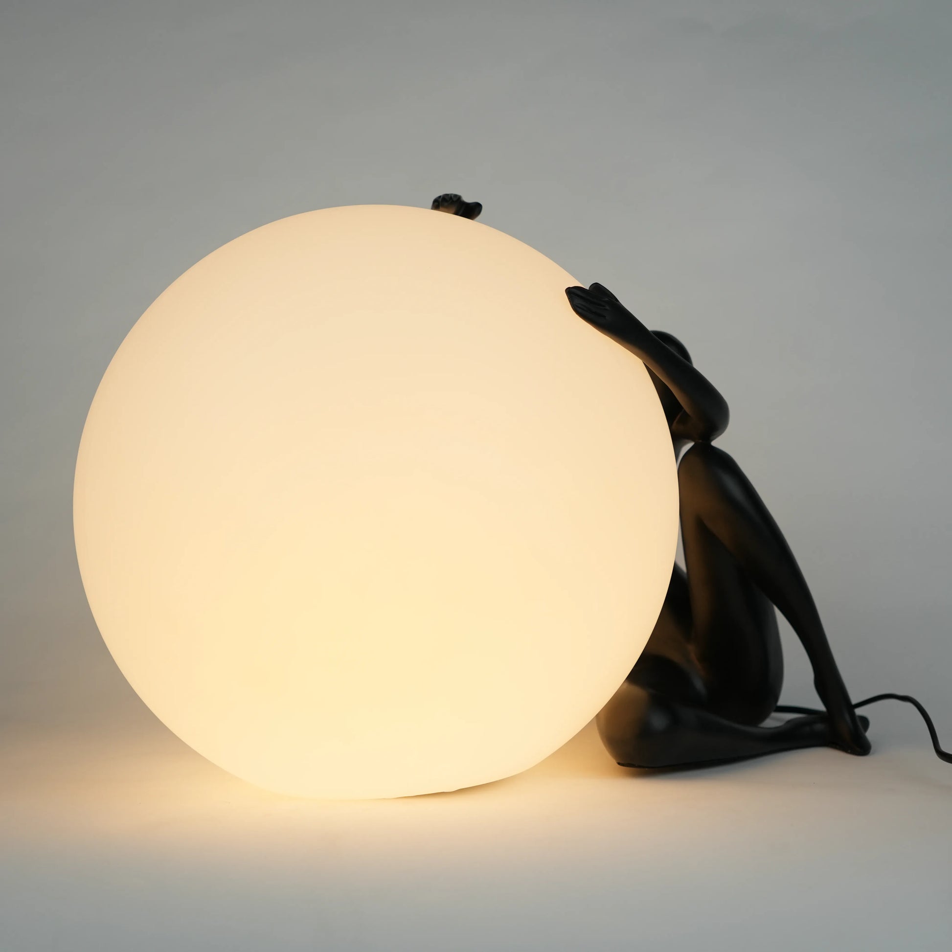 Black human sculpture lamp embracing glowing orb – Midnight Embrace Lamp