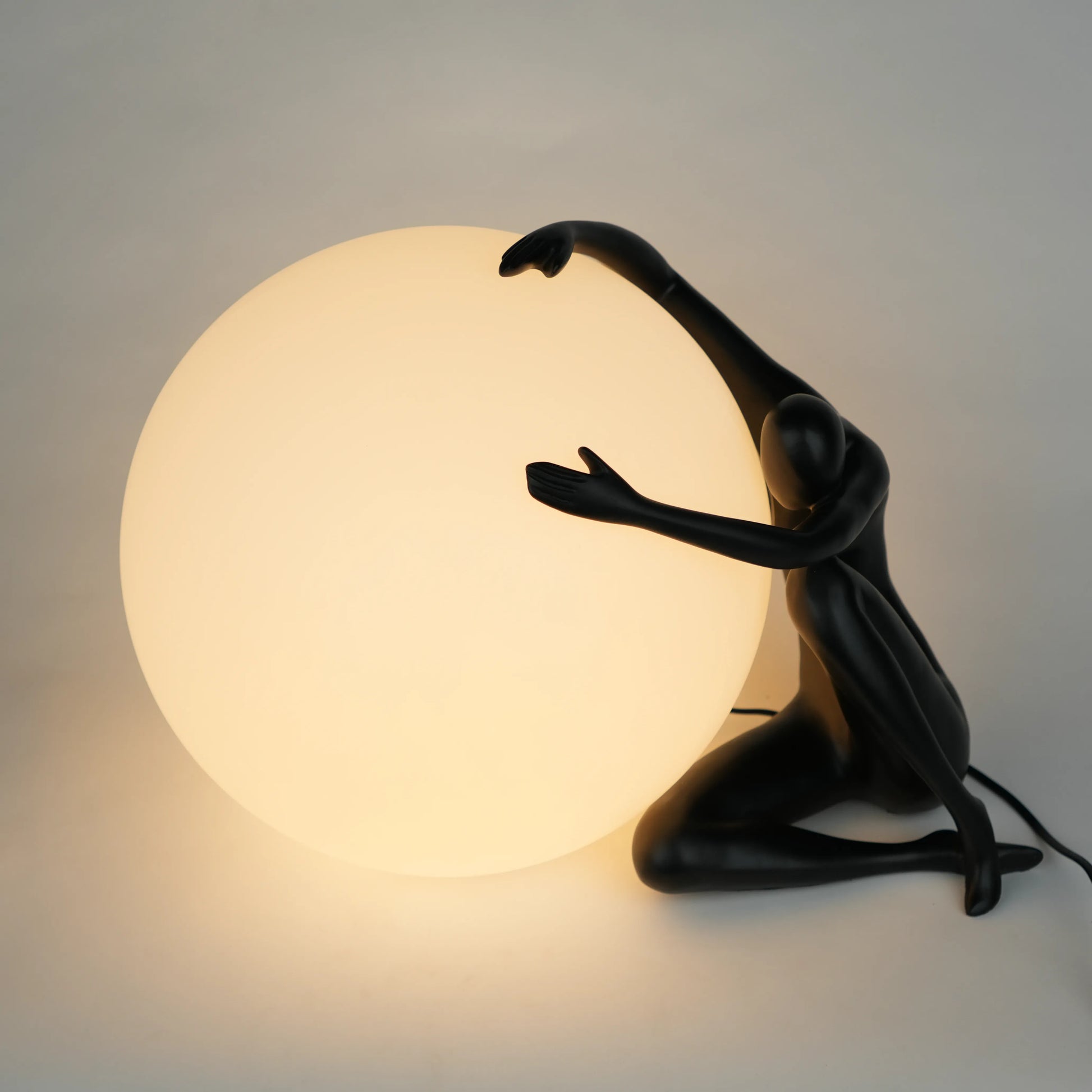Black human sculpture lamp embracing glowing orb – Midnight Embrace Lamp
