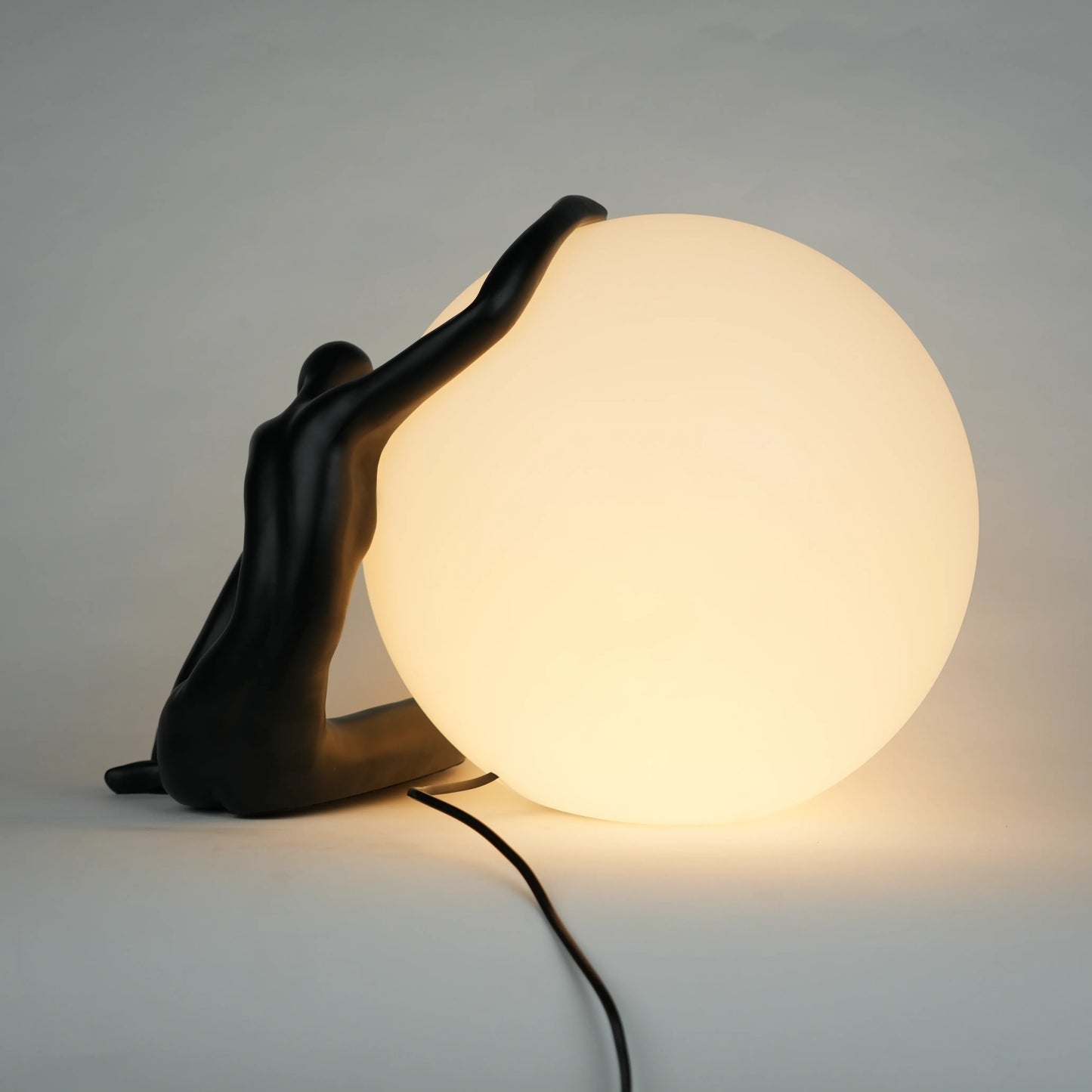Black human sculpture lamp embracing glowing orb – Midnight Embrace Lamp