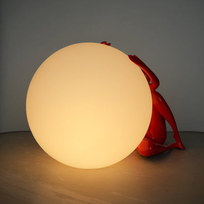 Crimson Embrace Lamp – Glossy red sculptural figure embracing a glowing orb – modern artistic table lamp by Ghar Art.
