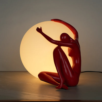Crimson Embrace Lamp – Glossy red sculptural figure embracing a glowing orb – modern artistic table lamp by Ghar Art.