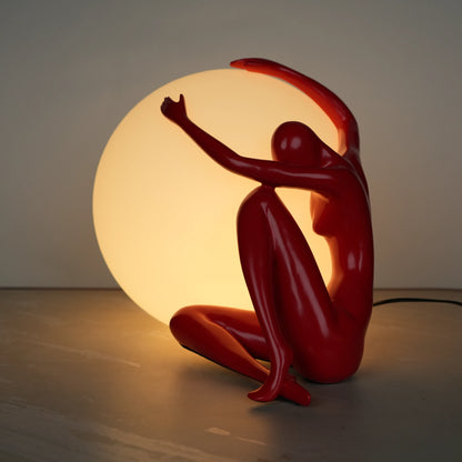Crimson Embrace Lamp – Glossy red sculptural figure embracing a glowing orb – modern artistic table lamp by Ghar Art.