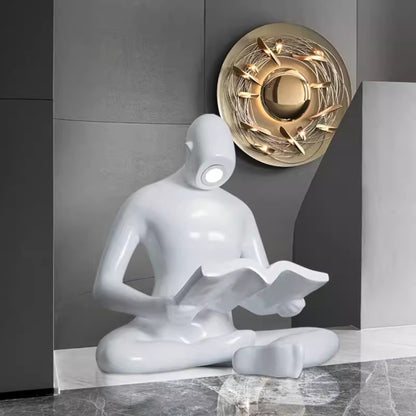 Glossy white reading sculpture lamp with abstract seated figure holding a book and built-in LED light.