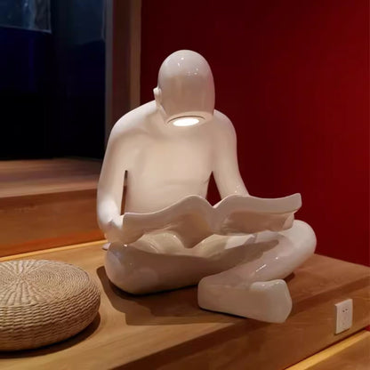 Glossy white reading sculpture lamp with abstract seated figure holding a book and built-in LED light.
