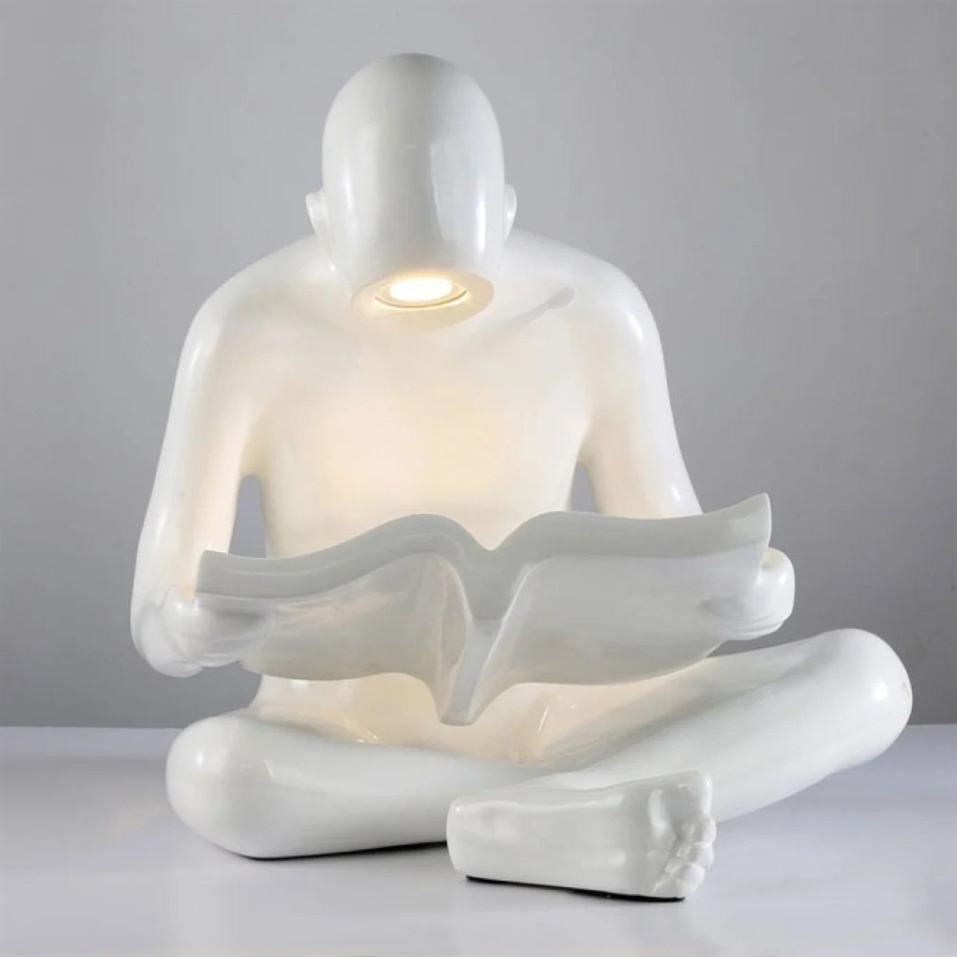 Glossy white reading sculpture lamp with abstract seated figure holding a book and built-in LED light.