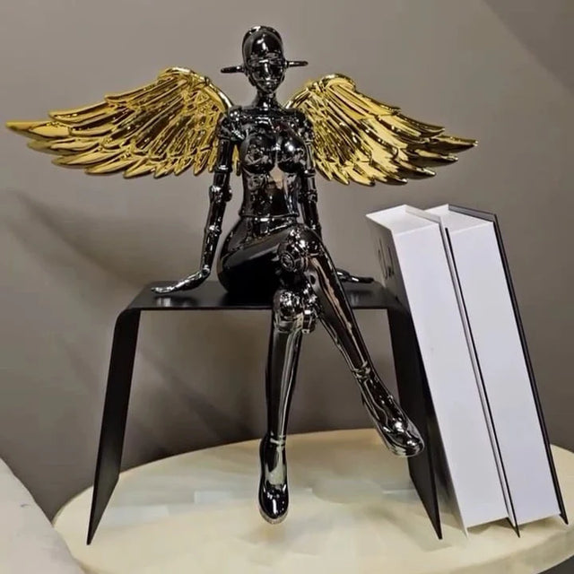 Chrome angel figurine with gold wings seated in a modern pose.