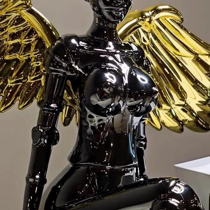 Chrome angel figurine with gold wings seated in a modern pose.
