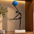 Abstract ballerina figurine sculpture balancing a blue sphere with graceful contemporary form