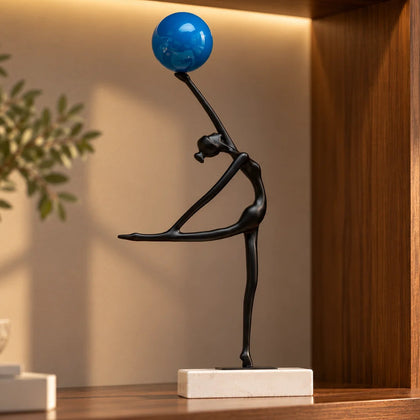 Abstract ballerina figurine sculpture balancing a blue sphere with graceful contemporary form