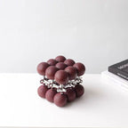 Maroon sphere cube beside Mondrian books
