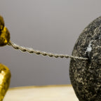 Golden resin figure pulling boulder, macro