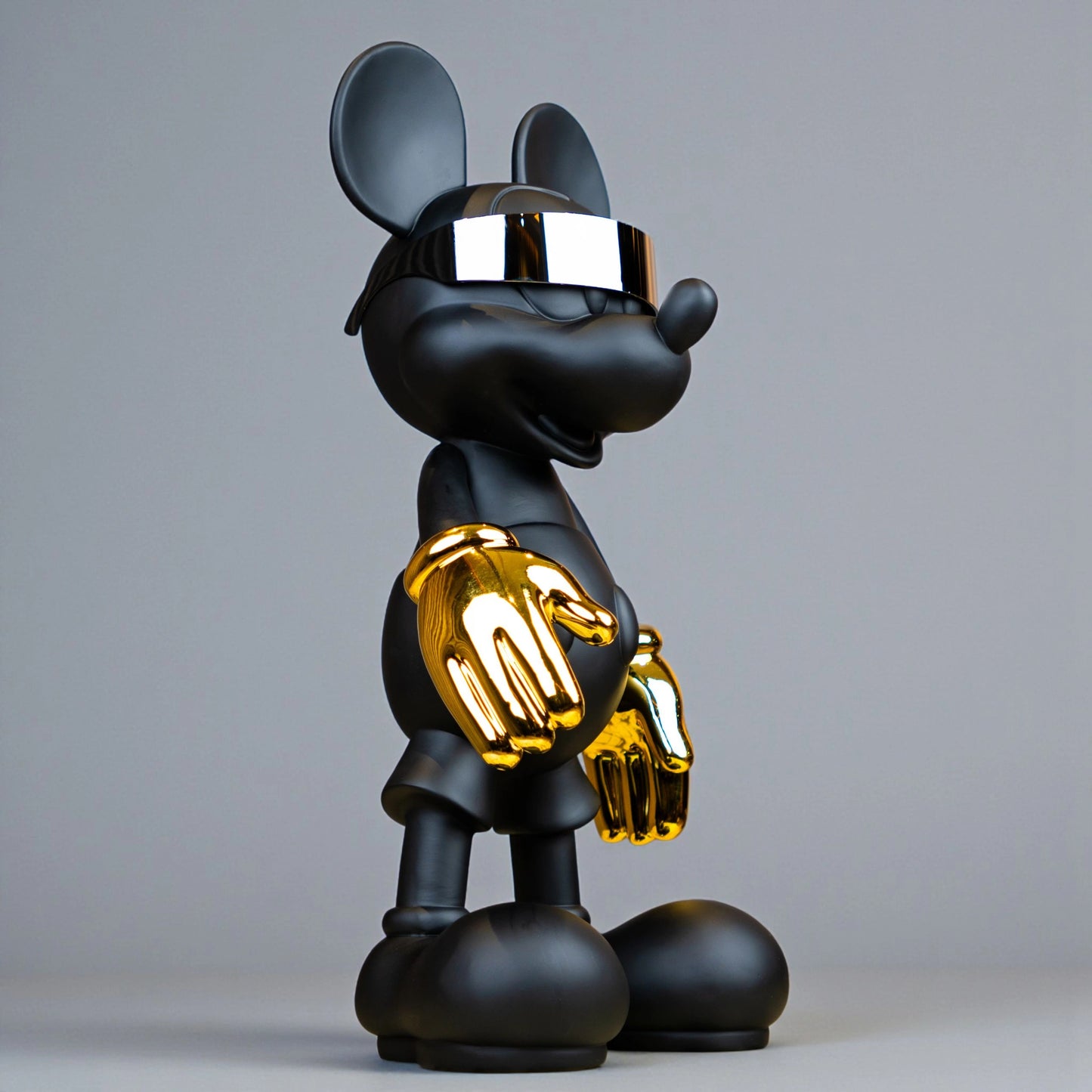 Black matte mascot figurine with gold gloves and chrome visor — Cyberpunk Mascot by Ghar Art, futuristic luxury tabletop decor sculpture.