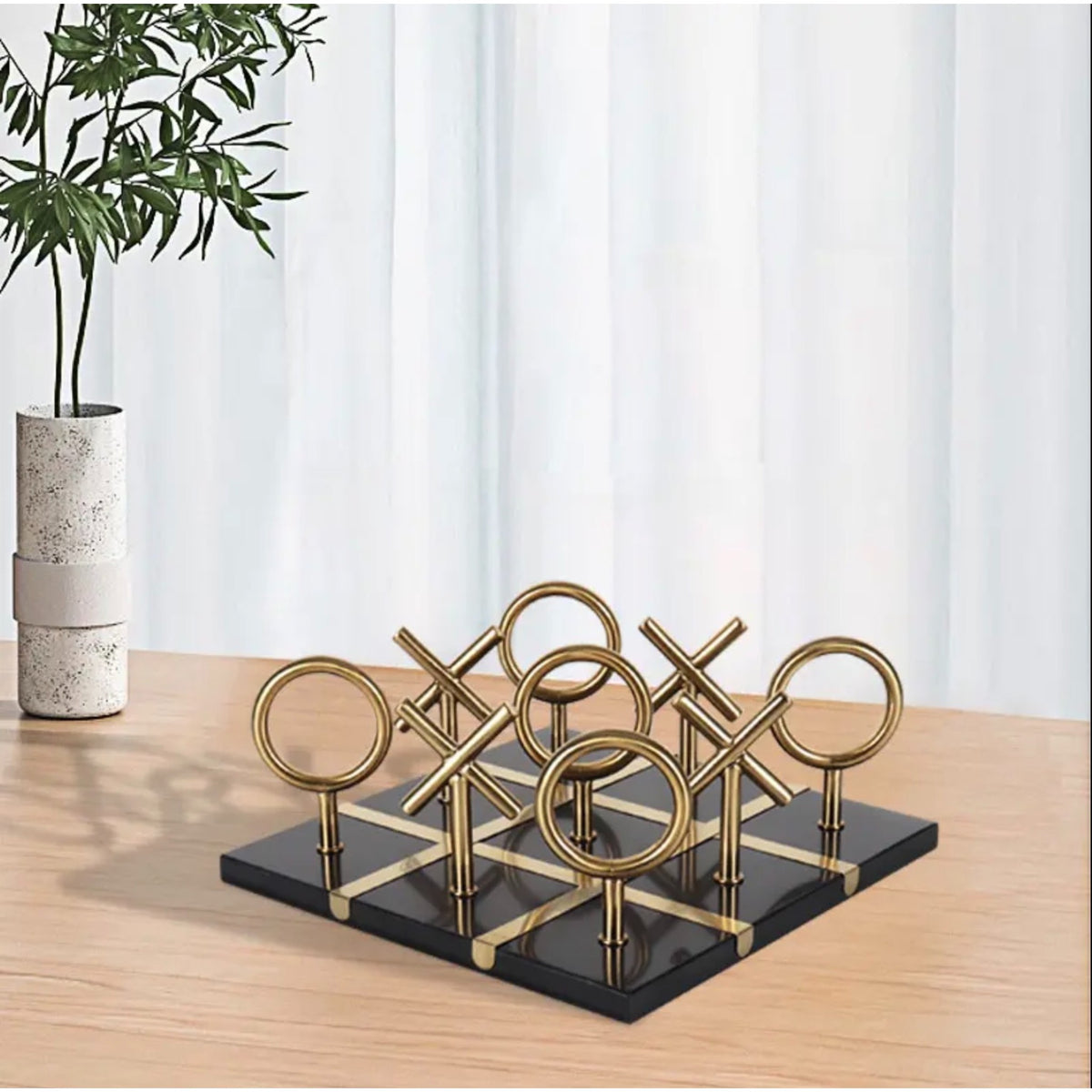 Tic Tac Toe on desk by speckled vase, styled