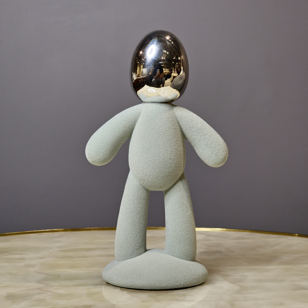 Contemporary abstract figurine with textured body and reflective metallic head.