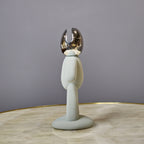 Minimalist human form decor object with textured surface and chrome head.