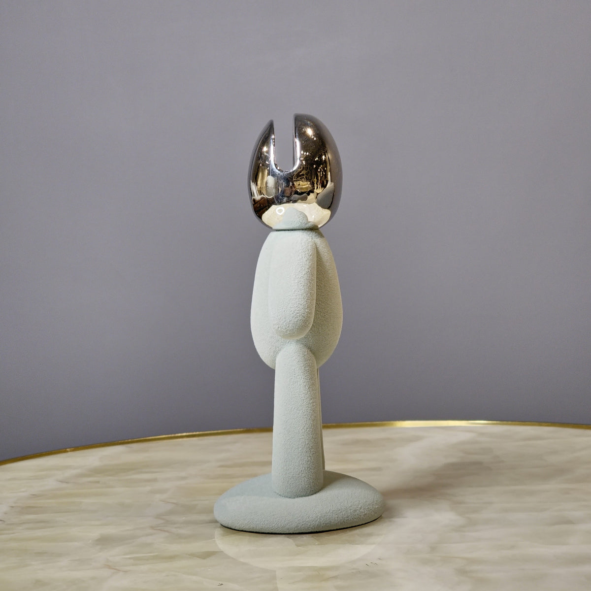Minimalist human form decor object with textured surface and chrome head.