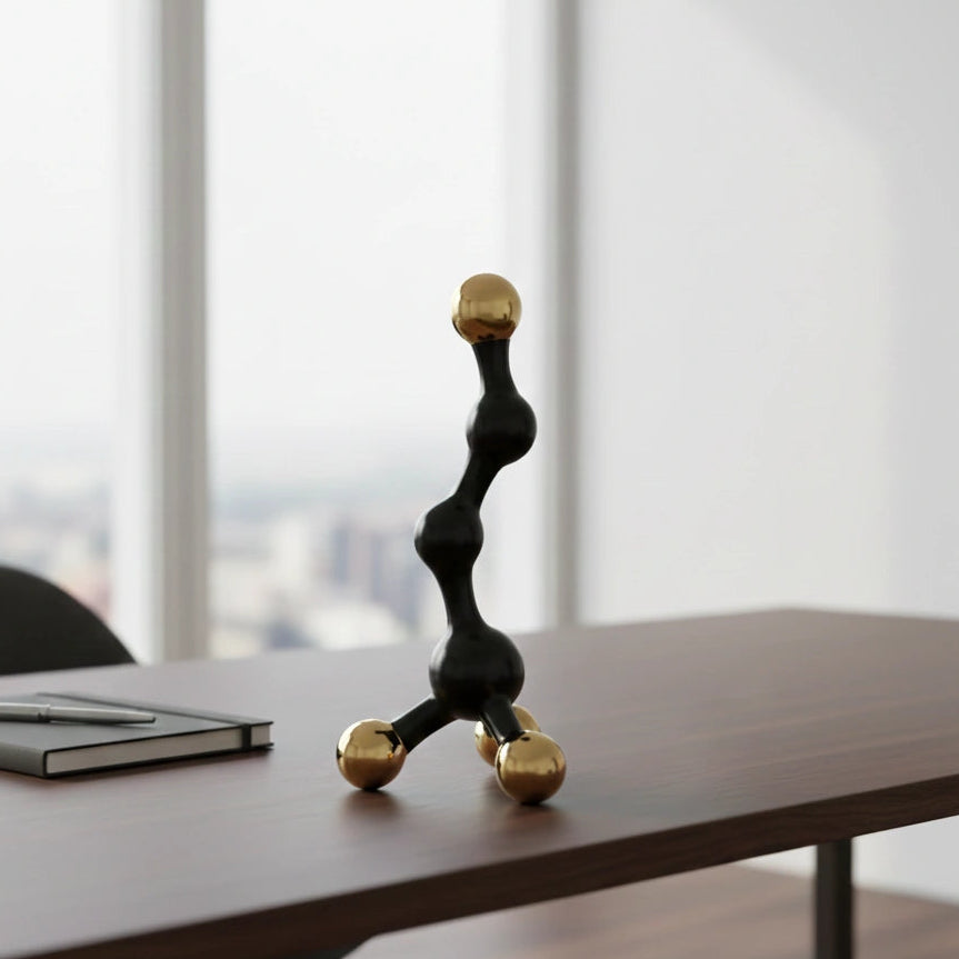 Decorative black and gold sculpture on a desk with a cityscape view through large windows.