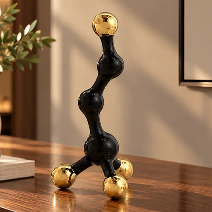 Decorative black and gold sculpture on a desk with a cityscape view through large windows.