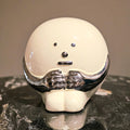 A modern ceramic accent with a curved, asymmetric shape and a smooth finish, displayed on a marble surface.