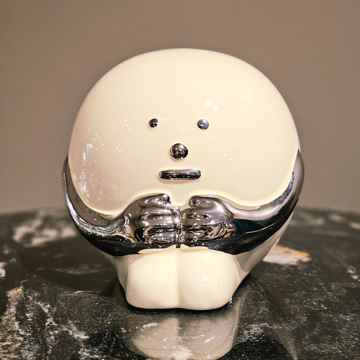A modern ceramic accent with a curved, asymmetric shape and a smooth finish, displayed on a marble surface.