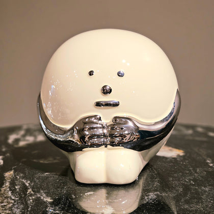 A modern ceramic accent with a curved, asymmetric shape and a smooth finish, displayed on a marble surface.