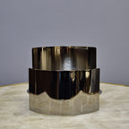 Contemporary curved metal stand for showcasing decorative objects.