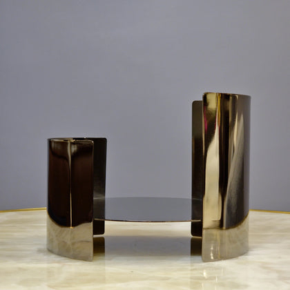 Contemporary metallic pedestal stand with curved design and reflective finish.